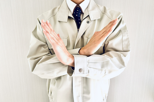 手をバツ印にしている作業服の人の画像