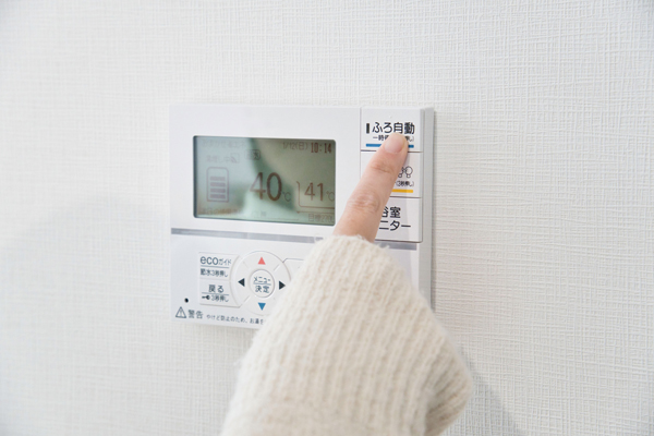 給湯器リモコンのボタンを指で押している画像